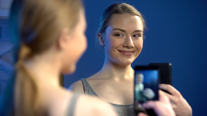 Beautiful young lady making selfie in mirror reflection for social nets, fun