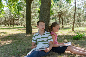 A boy and a girl do their homework in the park and get ready for school together.