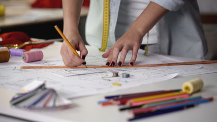 Designer drawing template for sewing new dress according to her sketches