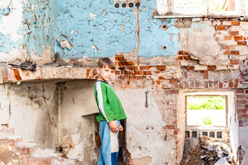 Orphaned children, poor child standing in a destroyed and abandoned building, staged photo.