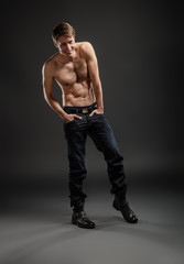 Fototapeta na wymiar Full length portrait of a sexy young man in jeans and shirtless posing at studio.