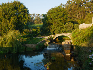 Ancient, stone Roman bridge over River Este in Vila do Conde, Portugal at sunset with soft golden light