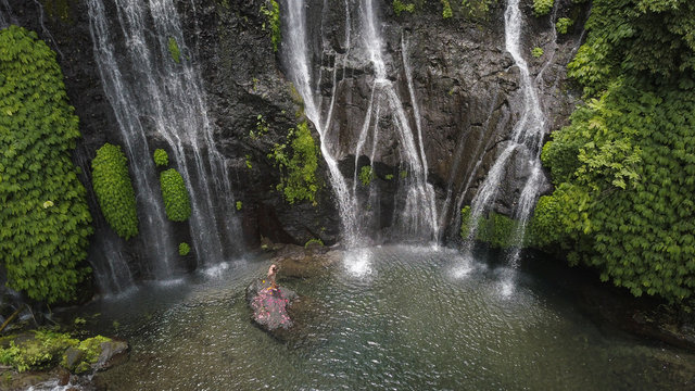 Aerial close up view of am man over a rock at the magnificient banyumala twin waterfalls, North Bali, Indonesia.