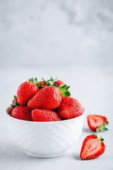 Fresh ripe delicious strawberry in a white bowl on a grey stone background