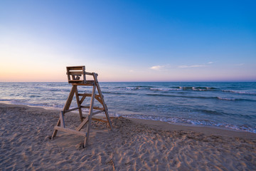 Mediterranean beach with wooden lifeguard chair in sunset time, Oliva Beach in Valencia province, Spain.