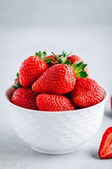 Fresh ripe delicious strawberry in a white bowl on a grey stone background