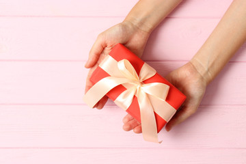 gift in female hands on a colored background top view.