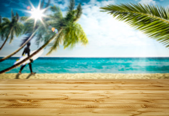 Wooden table top backround with beautiful calm ocean in distance. Some palm leaves above the wooden top board. Empty space for an advertising product.