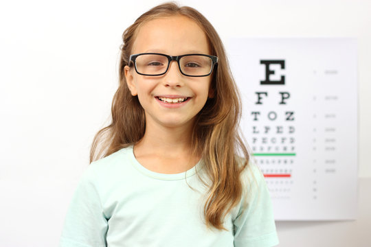 little cute cheerful girl passes an eye test in the office of an ophthalmologist