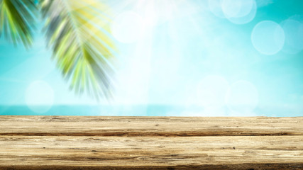 Wooden table top backround with beautiful calm ocean in distance. Some palm leaves above the wooden...