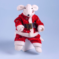 A cute white rat in a red Santa Claus suit is sitting on a white cube on a light blue background. Year of the white rat. Postcard Happy New Year 2020. Symbol of 2020 on the Eastern calendar. 