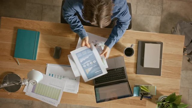 Businessman Sitting at His Desk in the Office Uses Laptop Computer, Working with Company Strategy Documents, Correcting Charts, Drawing Graphs and Statistics