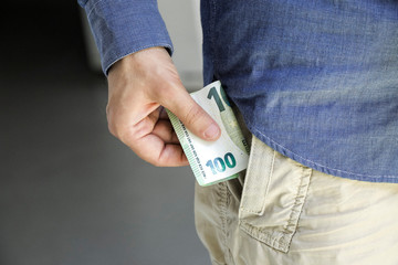 Hundred Euro bill in the hand and put the money in the pocket
