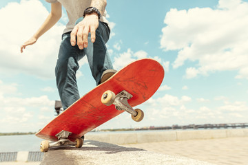 Skateboarder doing a trick at the city's street in sunny day. Young man in sneakers and cap riding and longboarding on the asphalt. Concept of leisure activity, sport, extreme, hobby and motion. - obrazy, fototapety, plakaty
