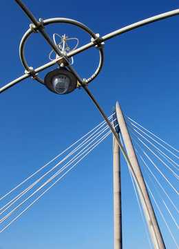a close up of the old Victorian lights on the pier at southport with the tower of the modern suspension bridge against a blue summer sky