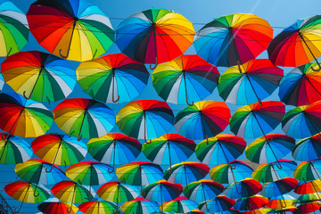 Fototapeta na wymiar outdoors decoration with many colorful umbrellas against blue sky and sun 