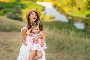 Fototapeta premium young mother and daughter walking through a rural area with a beautiful landscape