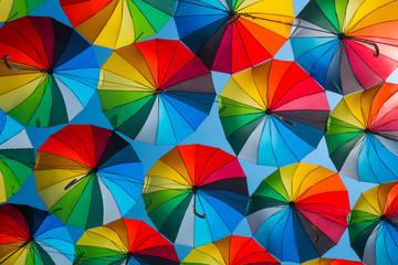 outdoors decoration with many colorful umbrellas against blue sky and sun	