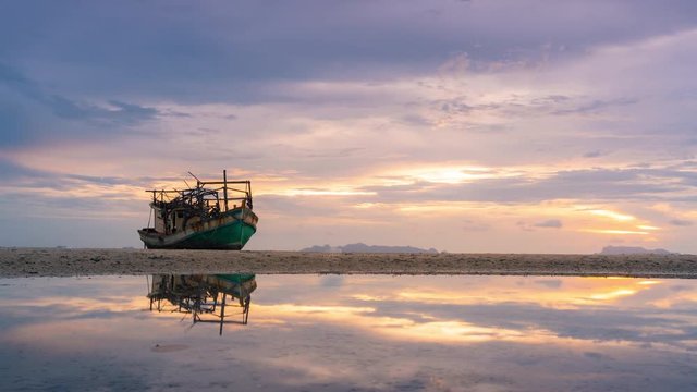 Old wrecking fishing boat beached and reflection on puddle in sunset time at Samui island, Suratthani, Thailand