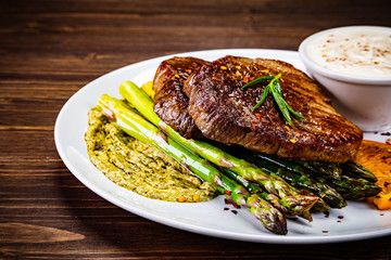 Grilled steak with asparagus on wooden background