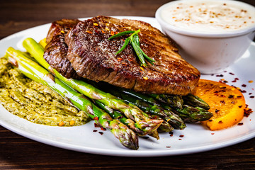 Grilled steak with asparagus on wooden background
