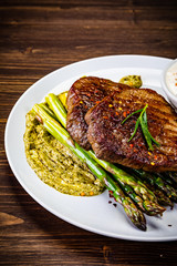 Grilled steak with asparagus on wooden background