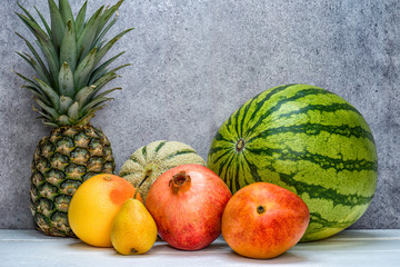 Melone, Ananas, Grapefruit, Birne und Granatapfel vor hellem Hintergrund