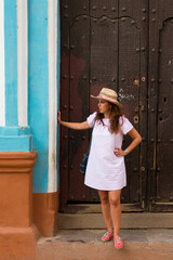 A pretty young woman with hat located at the door of an old colonial house in the colonial town of Trinidad (Cuba)