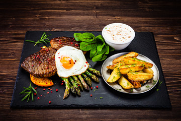 Grilled steak with asparagus, fried egg and french fries
