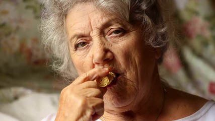 Happy elderly woman eating biscuit and smile
