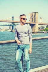 Young handsome American Man traveling in New York City, wearing gray, long sleeve T shirt,...
