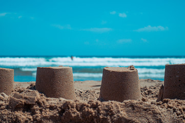 Fototapeta na wymiar Closeup of sandcastles on the sand of a beach, with the mediterranean sea in the background. Summer and vacations concept.