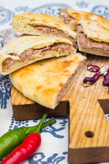 Lobiani pie - Georgian cuisine traditional food stuffed with red kidney or white beans (lobio) inside on wooden board and Lurji Supra tablecloth.