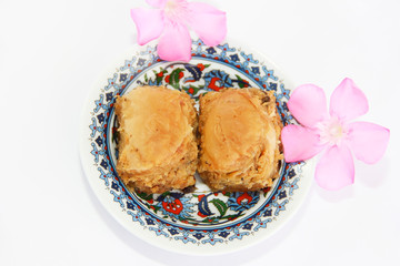 traditional Turkish sweetness baklava on plate with patterns and decor of pink flowers