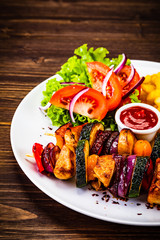 Kebabs - grilled meat with french fries and vegetables on wooden background