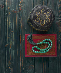 Islamic book Koran with rosary beads and muslim hat on wooden background. Islamic concept with copy space