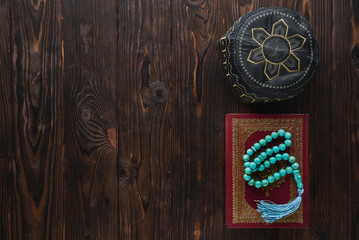 Koran with rosary beads and pray hat on wooden background. Islamic concept with copy space