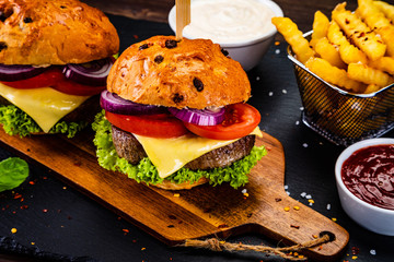 Tasty burgers with chips served on cutting board