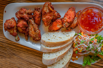 Grilled chicken wings, baked western potatoes, sweet Chinese souse and fresh salad in outdoor restaurant