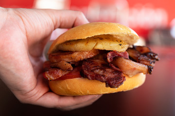 Hand taking a Delicious hamburger with pineapple and bacon
