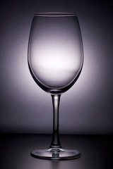 Wine glass on a long stem. In backlight.