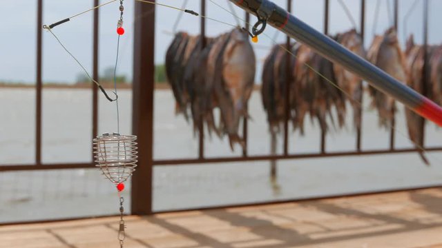 Feeder fishing gear on the background of dried fish hung in the sun. Pier near a small fishing village on the banks of the Volga River.