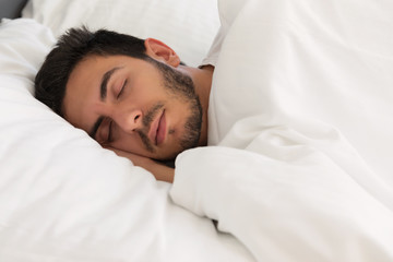 Young handsome man sleeping in his bed.