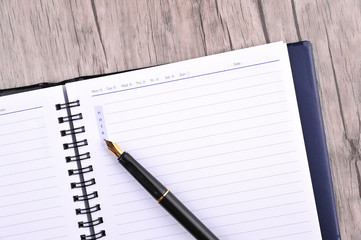 Notebook with fountain pen on wooden table