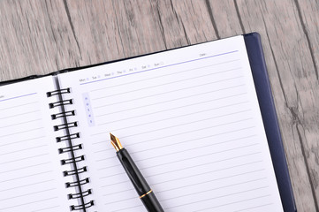 Notebook with fountain pen on wooden table