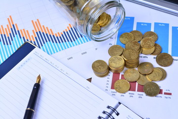 Graphs, charts, notebook, pen and coins. Business Concept