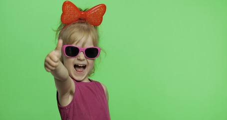 Positive girl in purple dress, sunglasses and red ribbon. Smile. Thumbs up