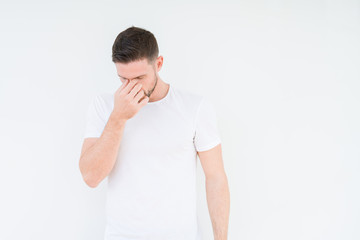 Young handsome man wearing casual white t-shirt over isolated background tired rubbing nose and eyes feeling fatigue and headache. Stress and frustration concept.