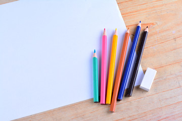 Blank paper and colorful pencils on the wooden table. View from above