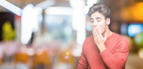 Young handsome man over isolated background bored yawning tired covering mouth with hand. Restless and sleepiness.